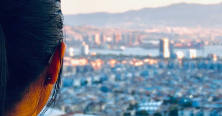 Hinterkopf einer Frau mit Panorama einer Stadt im Hintergrund