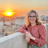 Portraitbild Pauli über den Dächern einer Stadt mit Sonnenuntergang