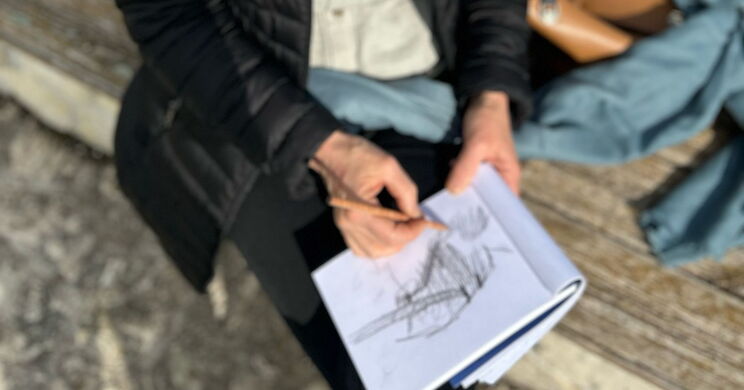 zeichnende Frau auf einer Holzbank