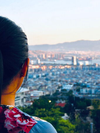 Hinterkopf einer Frau mit Panorama einer Stadt im Hintergrund