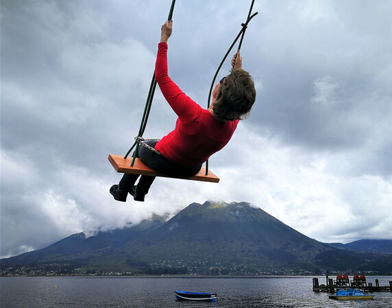 Esther Neufeld auf einer Schaukel mit Bergen und See im Hintergrund